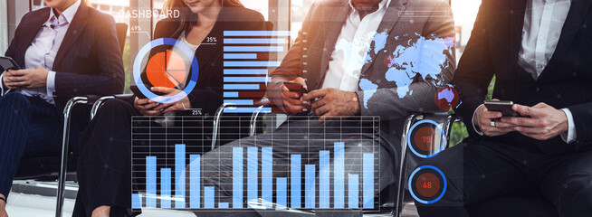 A group of business professionals engaged in using smartphones while analyzing various data graphs...