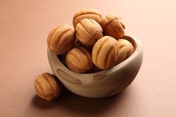 Delicious nut shaped cookies with boiled condensed milk in bowl on brown background, closeup