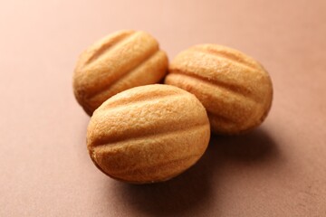 Delicious nut shaped cookies with boiled condensed milk on brown background, closeup
