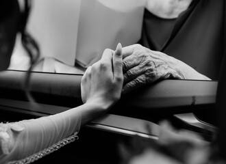Сlose up pictures anold woman with wrinkled hands holds her young granddaughter's hand