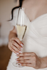 A close-up of a bride, without a face, holding a glass of champagne