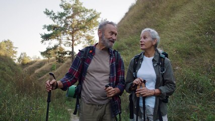 Elderly couple walks and woman explains route adjusting poles - Powered by Adobe