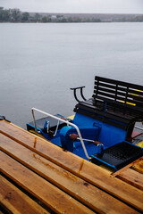 Wooden pier with swimming equipment near the lake in the rain, close-up