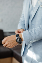 A close-up of a man in a jacket adjusting his watch on his wrist