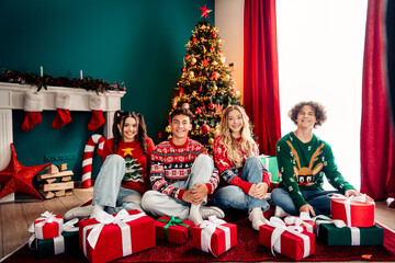 Happy teens enjoying Christmas celebration with sweaters and presents,
