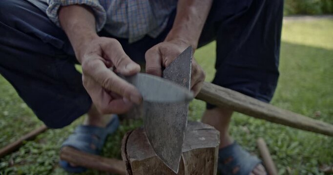 Watch as skilled hands meticulously sharpen an axe blade using a traditional whetstone, preparing the tool for work. The video captures the satisfying grinding sounds of the sharpening process.