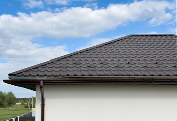 Brown metal tile roof with visible downspout and ridge