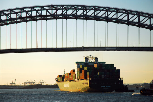 A large international container ship passes under the Bayonne Bridge in New York City, part of the trade and commerce between nations 