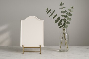 White ceramic board with gold stand and eucalyptus branches