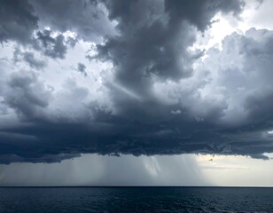 Dark, dramatic storm clouds over the ocean, with rain falling