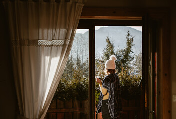 woman enjoying hot cup of tea on terrace in winter mountains ski holiday lodging