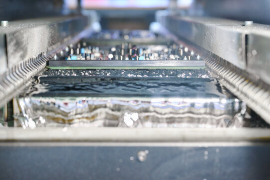 Detailed view of wave soldering process during PCB tinning in molten solder bath