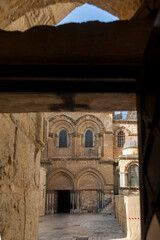 Jerusalem, Israel, 23 October 2025, The iconic, historic stone facade of the church of the holy sepulchre is framed through a dark, narrow doorway in the old city