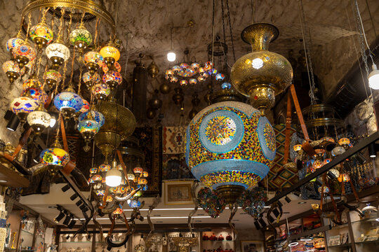 Jerusalem, Israel, 23 October 2025, Numerous vibrant and intricately designed turkish mosaic lamps and lanterns hang from the stone ceiling of a souvenir shop