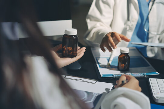 Two doctors and a female nurse meet at a table in the hospital, collaborating on medical tasks using laptops and computers - Powered by Adobe