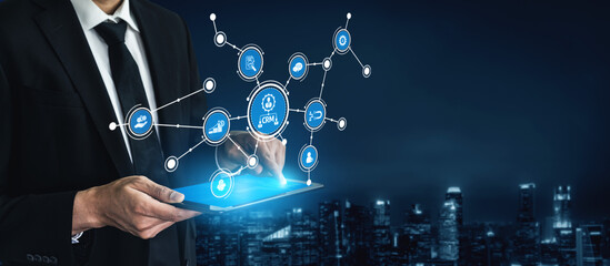 A businessman engaged with a tablet showcasing a futuristic digital interface over a city skyline. This image embodies technology, communication, and modern innovation. Tessel