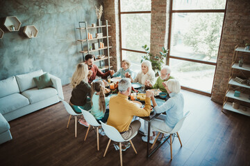 Family gathering around table for Thanksgiving dinner with friends and relatives in modern home creating happiness gratitude and holiday togetherness
