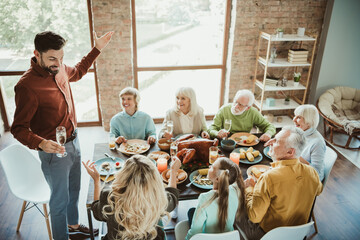 Funny toast at a warm family gathering as the host invites comfort and laughter during a big Thanksgiving dinner at home
