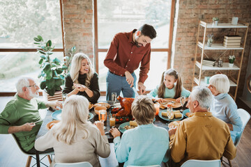 Joyful big family Thanksgiving feast around a long table with grandparents parents and kids sharing laughter food and love