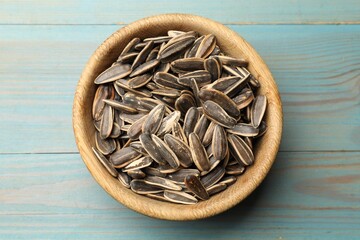 Sunflower seeds in bowl on light blue wooden table, top view