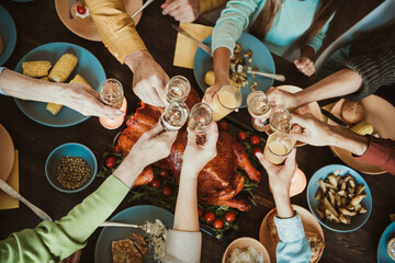 Friends and family gather around a festive dining table to raise glasses in a joyful thanksgiving toast and share gratitude savoring turkey and seasonal