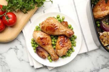 Grilled chicken drumsticks served with green peas on white marble table, flat lay
