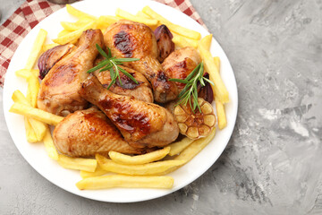 Grilled chicken drumsticks with french fries and spices on grey table, above view. Space for text