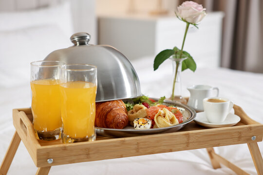 Tray with delicious breakfast and rose on bed in hotel room, closeup - Powered by Adobe