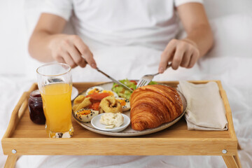 Man having delicious breakfast in bed, closeup. Hotel room service