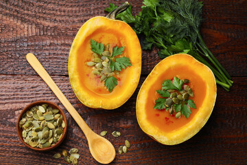 Tasty pumpkin cream soup with seeds, parsley and dill on wooden table, flat lay