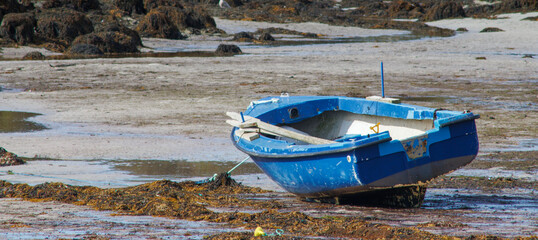 Blue rowing boat stranded in the sand with the tide out