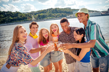 Group of diverse friends celebrating together at a lakeside gathering during a sunny summer day in a scenic urban area