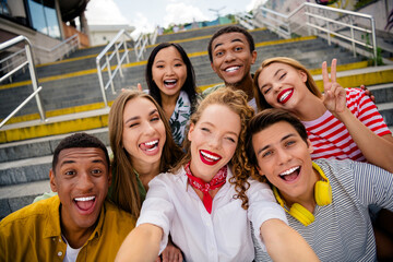 Funny young friends enjoying a cheerful moment together outdoors on urban stairs during a sunny summer day