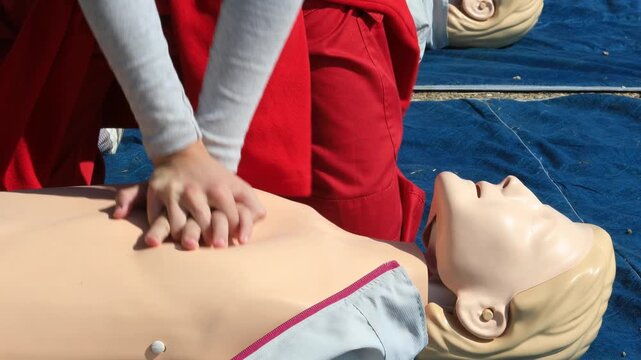 Cardiopulmonary resuscitation (CPR) training demonstration showing paramedic performing chest compressions on adult CPR dummy during first aid course
