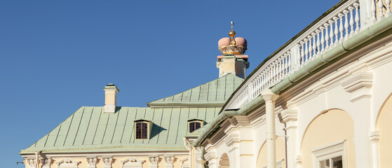 Architectural details of the Grand Menshikov Palace in Oranienbaum with its mint-green roof, golden crown, and clear blue autumn sky.