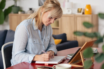 Woman writing notes in planner working from home