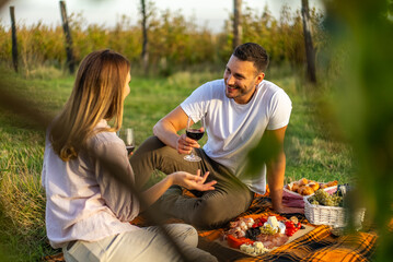 Couple enjoying a picnic with wine and charcuterie in a vineyard setting