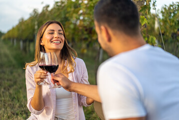 Couple toasting with red wine in a vineyard, celebrating a special moment