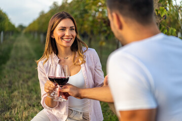 Couple toasting with red wine in a vineyard during a romantic date