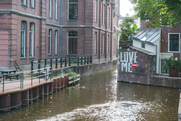 August 20, 2025, Amsterdam, Netherlands, view of a river on Grimburgwal Street with a sign reading “Love Me” in the background.