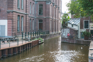 August 20, 2025, Amsterdam, Netherlands, view of a river on Grimburgwal Street with a sign reading “Love Me” in the background.