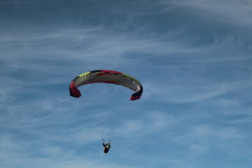 Paraglider flying under a blue sky with thin clouds in Chile