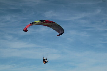 Paraglider flying under a blue sky with thin clouds in Chile