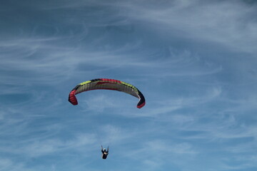 Paraglider flying under a blue sky with thin clouds in Chile