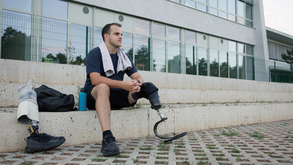 Individual resting on steps with a prosthetic leg, while enjoying the view at a recreational area on a sunny day.