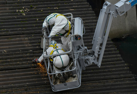 Deux ouvriers travaillent au d&eacute;samiantage d'une toiture