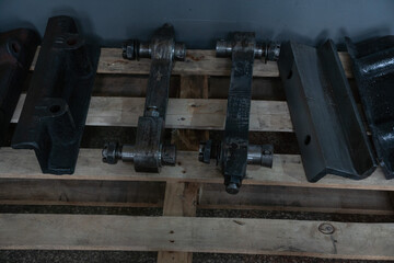 Heavy steel connecting rods and locomotive suspension parts displayed on a wooden pallet inside the locomotive museum Povorotny Krug