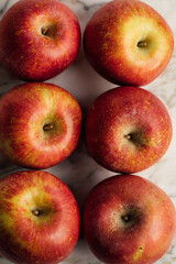 top down view of six fuji apples on white marble