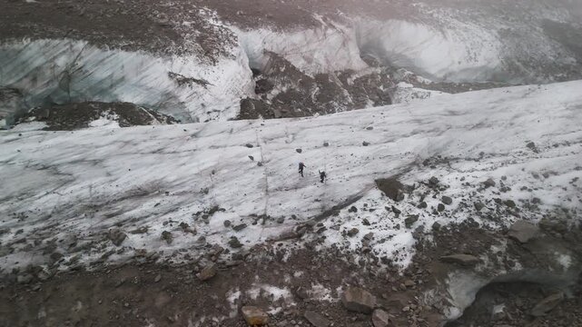 Zwei winzig erscheinende Personen laufen &uuml;ber den Gletscher Mer de Glace in den franz&ouml;sischen Alpen nahe Chamonix im Mont-Blanc Massiv.