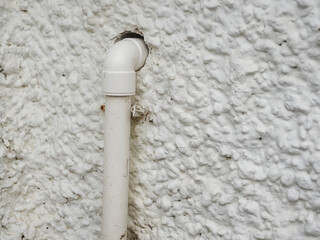 A white pipe is sticking out of a wall, there is no sealant. Poor job or temporary solution.